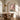 Dusty pink hydrangea oil painting in a thin gold frame above a dark wood sideboard in a refined dining room with brass candlesticks