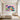 Cheerful hand painted colorful pattern flower oil painting hanging above an upholstered bed frame in a cozy modern creative bedroom setup.