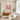 Large hand-painted abstract flower canvas with vibrant coral, magenta and yellow brushwork on a white wall beside a floor lamp in a modern living room