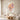 Cascading coral and peach floral bouquet oil painting in a thin gold frame above a cream boucle sofa in a bright modern living room
