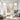 Hand painted pastel abstract floral oil painting with thick knife texture hanging above a beige fabric sofa in a bright modern living room.