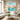 Hand painted turquoise and pink abstract floral square oil painting with long drips hanging over a white sofa in a coastal living room.