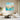 Large teal and peach abstract flower canvas wall art displaying fluid dripping brushwork in a modern bright living room setup.