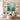 Framed square mint teal floral canvas artwork bringing fresh botanical energy above a light wooden sideboard in a serene living room.