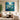 Framed square dark teal floral canvas artwork bringing dramatic night garden light above a sleek credenza in a contemporary living room.