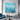 Textured blue ocean wave abstract canvas painting hanging above a gray console unit on a modern marble tiled wall.